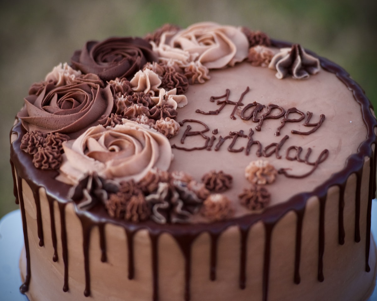A chocolate cake with frosting roses and Happy Birthday written in icing